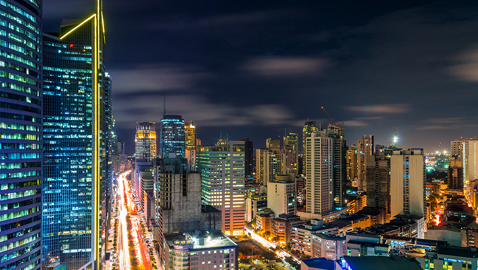 Makati cityscape at night with lights from buildings and cars.