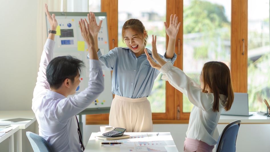 Young professionals smiling and raising their hands