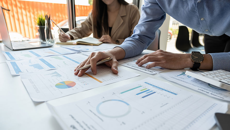 Man and woman scrutinizing printed charts on a table