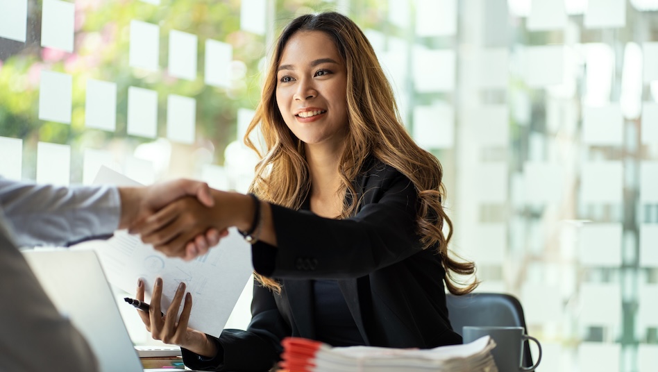Attractive Asian businesswoman shakes hands with a successful male entrepreneur in the business meeting. Male boss shakes hands and welcomes the new female employee.
